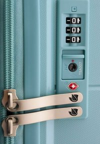 Maleta rígida de color azul claro con cremallera y candado aprobado por la TSA, que presenta una combinación de tres dígitos, tiradores de cremallera de metal y superficie texturizada.