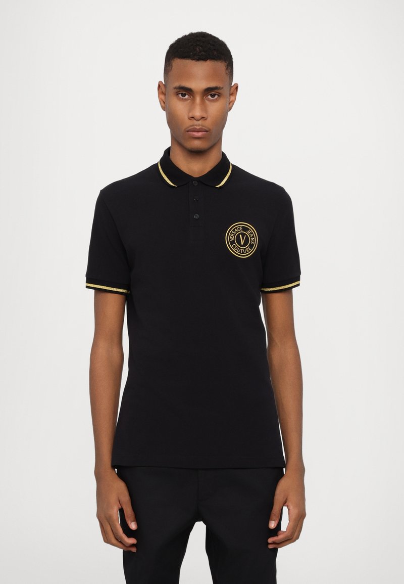 Polo shirt din bumbac negru cu accente aurii pe guler și mâneci. Prezintă un logo rotund pe partea stângă a pieptului. Croială clasică, mâneci scurte.
