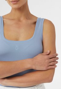 Hellblaues, tailliertes Tanktop mit quadratischem Ausschnitt, aus weichem Jersey-Stoff gefertigt; mit einem dezenten Logo auf der Vorderseite.
