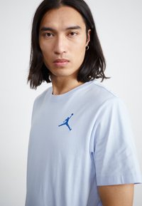 Lyseblå bomulds t-shirt med rund hals og korte ærmer. Udstyret med et blåt broderet Jumpman-logo på venstre bryst.