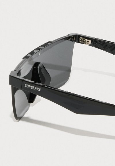 Czarne okulary przeciwsłoneczne o błyszczącej powierzchni, kanciastej ramie, ciemnych soczewkach i teksturowanych akcentach na zausznikach. Zawierają logo "Burberry".