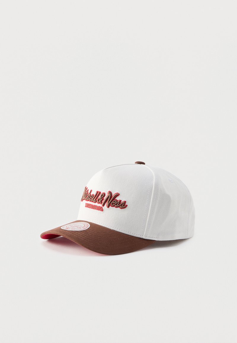 Λευκό και καφέ καπέλο μπέιζμπολ με τη λέξη «Mitchell & Ness» κεντημένη με κόκκινα γράμματα στο εμπρόσθιο πάνελ, τοποθετημένο σε λευκό φόντο.