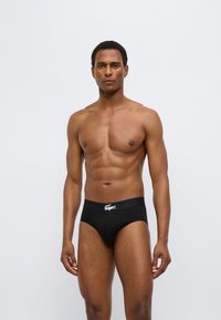 Μαύρα βαμβακερά εσώρουχα με στενή εφαρμογή, με ελαστική μέση με λογότυπο. Ομαλή υφή και μινιμαλιστικός σχεδιασμός.