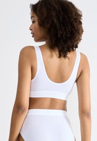 Witte katoenen bh met een ronde rug, brede bandjes en een naadloos ontwerp. Gepaard met bijpassende high-waisted slipjes met elastische banden.