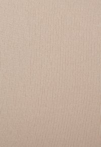 Lichtroze rekbare stof met een zachte ribbelstructuur. De close-up onthult fijne lijntjes en een gelijkmatig oppervlak zonder zichtbare patronen of accenten.