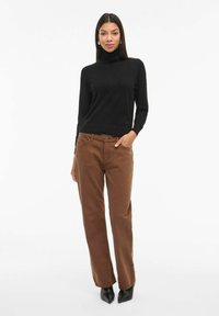 Zwarte coltrui gecombineerd met bruine rechte broek en zwarte puntige hakken. Glad textuur, een getailleerde silhoët, minimale details.