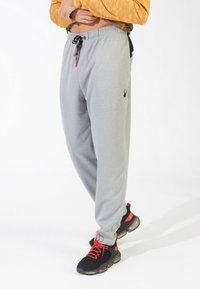 Grå sweatpants lavet af blødt materiale, med elastisk talje, sidelommer og et lille sort logo. Stylet med sorte sneakers.