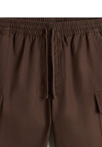 Bruine cargoshorts met een elastische tailleband met trekkoord, twee zijzakken en een gladde, gestructureerde stof.