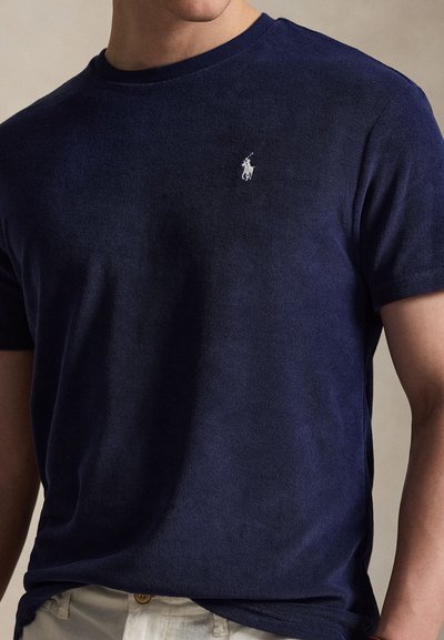 Μπλε ναυτικό βαμβακερό T-shirt με κοντά μανίκια, στρογγυλή λαιμόκοψη και μικρό λευκό κεντημένο λογότυπο στο στήθος. Λεπτή υφή, casual εφαρμογή.