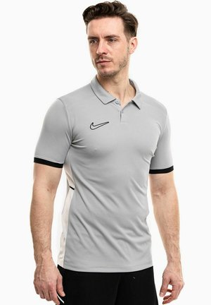 Polo grigio realizzato in tessuto morbido con logo Nike nero e accenti neri a contrasto sulle maniche corte. Design con colletto classico.