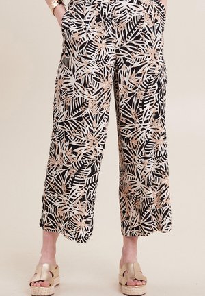 Zwart-witte wijde broek met een botanische bladerenprint in metallic rosegoud, voorzien van zijzakken en een casual pasvorm. G gedragen met gouden platform sandalen.