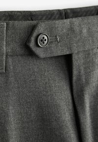 Los pantalones gris oscuro presentan una textura suave, un diseño ajustado y un cierre de botón con un botón negro de cuatro agujeros en la cintura.