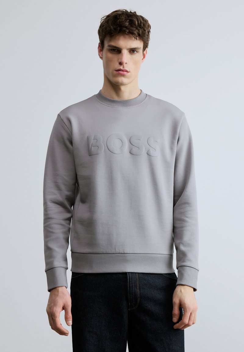Γκρι φούτερ με υφασμάτινο, ανάγλυφο λογότυπο "BOSS" στο μπροστινό μέρος. Διαθέτει στρογγυλή λαιμόκοψη και ριμπ τελειώματα στα μανίκια και την άκρη. Απλός, λιτός σχεδιασμός.