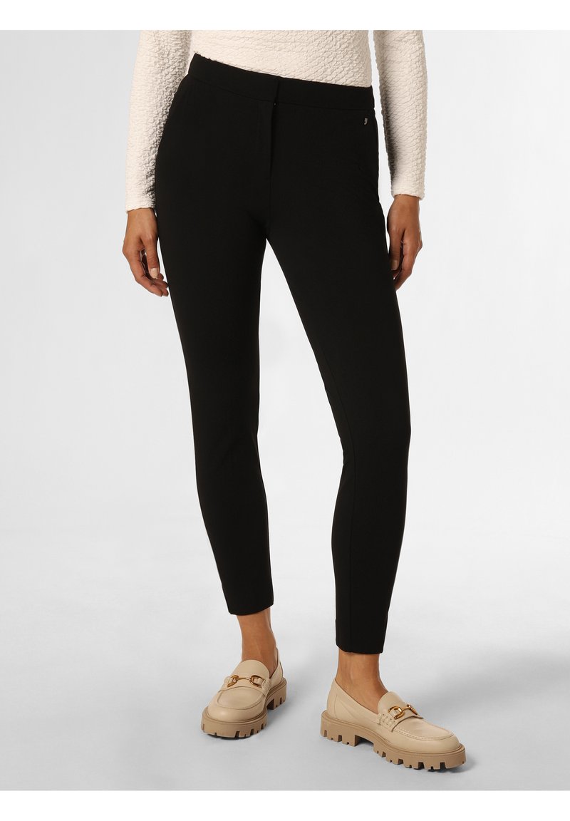 Black, fitted pants made of stretch fabric with a smooth texture. Features a mid-rise waist and side pockets; paired with beige loafers.
