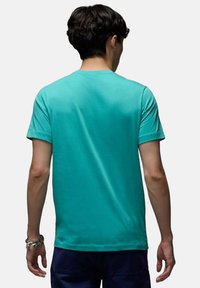 T-shirt in cotone turchese con collo rotondo, maniche corte e vestibilità rilassata, caratterizzato da una texture liscia e senza motivi o loghi visibili.