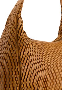 Perforated bruine leren handtas met een ronde vorm, voorzien van een enkele schouderband en een gestructureerd oppervlak met kleine ronde uitsparingen.