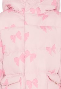 Giacca puffer rosa chiaro con cappuccio, caratterizzata da un motivo a stampa di piccoli fiocchi rosa, due tasche frontali e sezioni trapuntate.