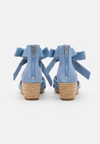Modré semišové klínové sandály s juty, s bočním zipem a stuhovými vázankami kolem kotníku. Hladká textura a otevřený design.