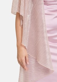 Doorzichtige, lichtroze sjaal met een golvende textuur en een metallic glans; hangt losjes met open mouwen en een ruwe zoom.