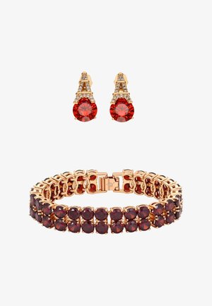 Bracciale d'oro con due file di gemme rosso scuro e orecchini abbinati in oro con pietre triangolari trasparenti e grandi gemme rosse.