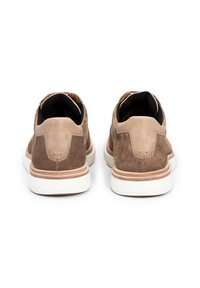 Bottines en suede marron à enfiler avec un accent en cuir lisse au talon et une semelle en caoutchouc blanc. Vue arrière montrant le design et les détails de couture.