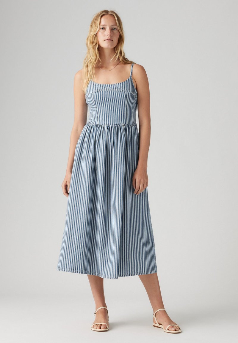 Robe midi rayée bleu et blanc avec des fines bretelles, taille froncée et jupe fluide. Tissu léger et silhouette décontractée.