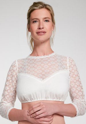 Weißes Spitzen-Crop-Top mit langen Ärmeln, das eine durchsichtige Spitzenapplikation, einen elastischen Taillenbund und einen gewellten Ausschnitt aufweist. Aus weichem Jersey-Stoff.
