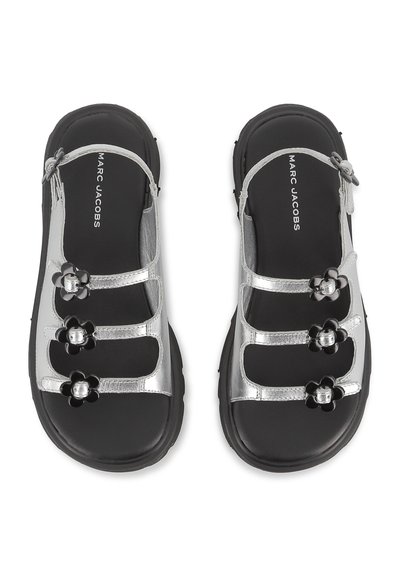 Ασημένια μεταλλικά σανδάλια με τρία μαύρα λουλούδια, μαύρες σόλες και ρυθμιζόμενους ιμάντες. Διαθέτουν λεία επιφάνεια και κομψό σχέδιο.