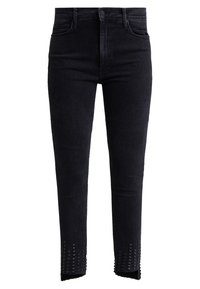 Skinny black jeans in a stretchy denim material, featuring a unique cut-out hem with pyramid stud details along the edge.