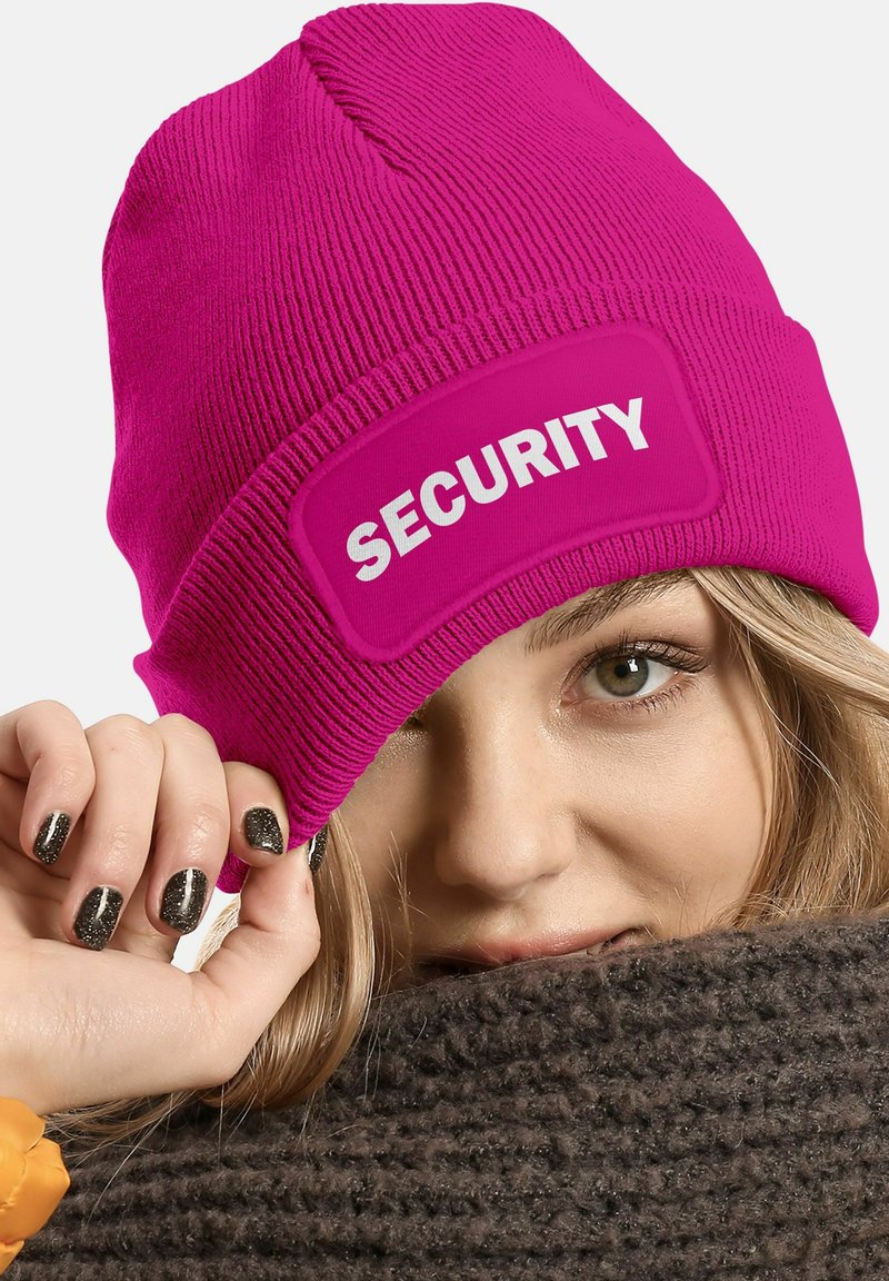 Pink knit beanie featuring a prominent "SECURITY" patch in white. Close-fitting design, ribbed texture, worn at an angle.