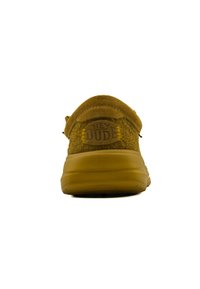 Scarpe slip-on in tessuto marrone con retro arrotondato, caratterizzate da una patch con logo e cuciture gialle sulla tomaia morbida, e una suola flessibile.
