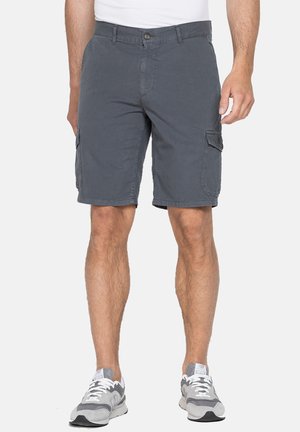 Shorts cargo gris avec poches latérales, en tissu léger. Dotés d'une fermeture à bouton et de passants de ceinture. Portés avec des chaussures de sport grises.
