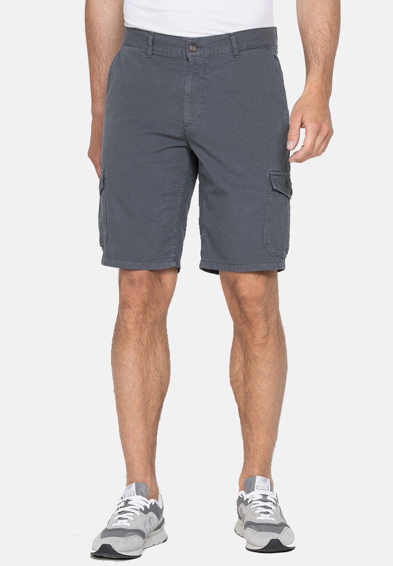 Pantaloni cargo grigi con tasche laterali, realizzati in tessuto leggero. Presentano una chiusura con bottoni e passanti per la cintura. Indossati con scarpe da ginnastica grigie.