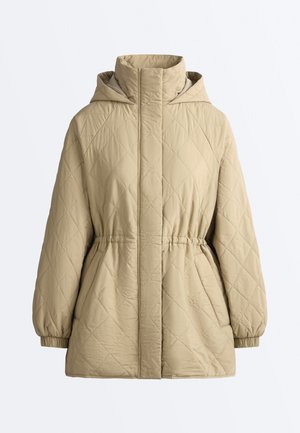 Beige quiltet jakke med høj krave, hætte, elastisk talje og manchetter samt forlommer mod en ensfarvet hvid baggrund.