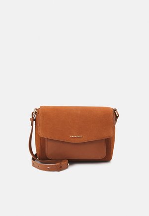 Bruine suede schoudertas met een textuurflap, leren accenten en een verstelbare schouderband; heeft een gouden logo aan de voorkant.