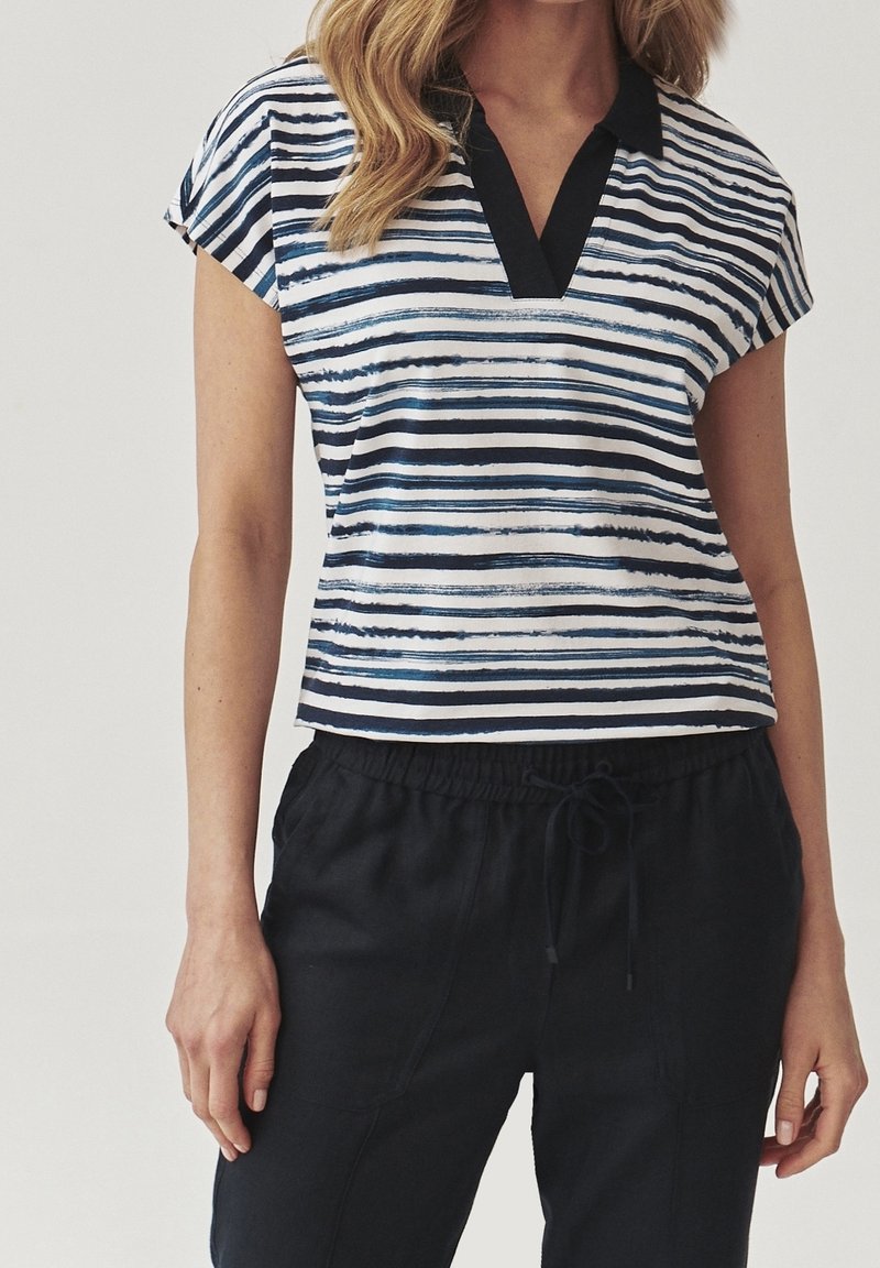 Haut à manches courtes rayé aux couleurs bleu marine et blanc, col en V, coupe décontractée, associé à un pantalon à taille élastique sombre.