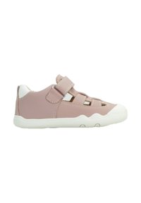 Zapatilla deportiva de color rosa claro con parte superior sintética, suela de goma blanca y tiras de Velcro. Presenta recortes para la ventilación y acentos texturizados.