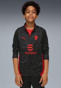 Schwarzer Sportpullover mit roten Akzenten, langen Ärmeln, halbem Reißverschluss vorne und strukturiertem Muster. Beinhaltet ein Logo und den Text "FOOTBALL" auf der Vorderseite.