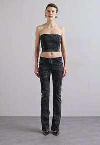 Black denim crop top and matching flared jeans, featuring a faded texture, front pockets, and a streamlined design. High-heeled shoes complete the look.