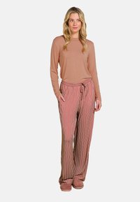 Long-sleeve, beige top paired with striped, wide-leg pants in red, white, and orange. Pants feature an elastic waistband with a drawstring.