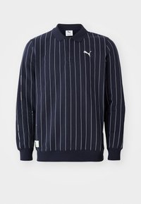Marineblå polo skjorte med hvide lodrette striber, kravedesign, lange ærmer, ribbede manchetter og et lille logo på venstre bryst.