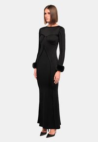 Schwarzes langärmliges Kleid mit einem taillierten Oberteil und Nahtdetails sowie Pelzärmeln. Glatte Textur und bodenlänges Design.