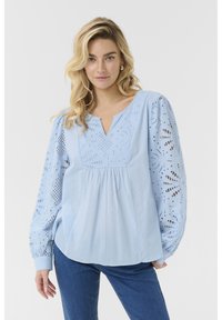 Svetlo modra bluzica z V-izrezom, napihnjenimi dolgimi rokavi z čipkastim detajlom in zbranimi pasom za ohlapno prileganje. Gladka tekstura blaga.