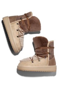 Botas de ante en tonos marrón y tostado con un suave forro de piel, que presentan un diseño de caña alta, cordones decorativos y una suela de goma texturizada.