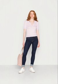 Top curto de manga curta, de cor lilás clara e com riscas, jeans skinny escuros, sapatilhas brancas e uma mala tote rosa suave. Design simples e contemporâneo.