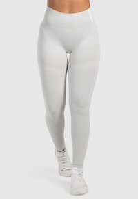 Hellgraue Leggings mit hohem Bündchen, gerippter Textur und subtilen Seitenpaneelen. Mit Logo auf dem Bündchen und glatter Oberfläche.