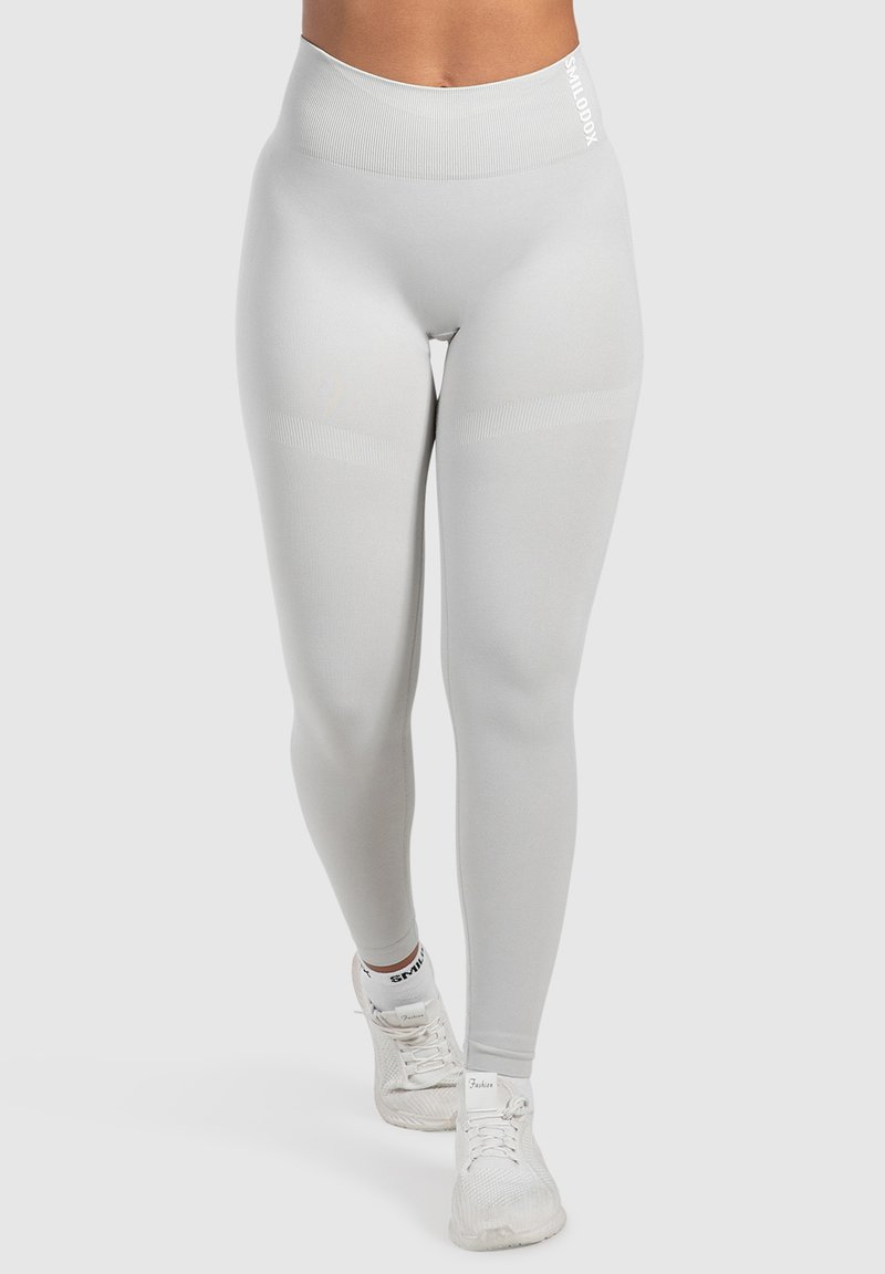 Hellgraue Leggings mit hohem Bündchen, gerippter Textur und subtilen Seitenpaneelen. Mit Logo auf dem Bündchen und glatter Oberfläche.