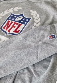 Gray sweatshirt featuring NFL logo in red and blue with a football graphic, surrounded by laurel leaves. Soft fabric with ribbed cuffs.