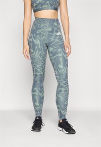 Leggings sportivi a vita alta di colore verde con un motivo astratto testurizzato. Presentano un elastico in vita e tre strisce bianche sui lati.