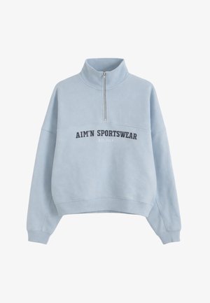 Sweat-shirt bleu clair à demi-fermeture éclair avec poignets et ourlet côtelés, arborant le texte "AIM'N SPORTSWEAR EST 2013" sur le devant.
